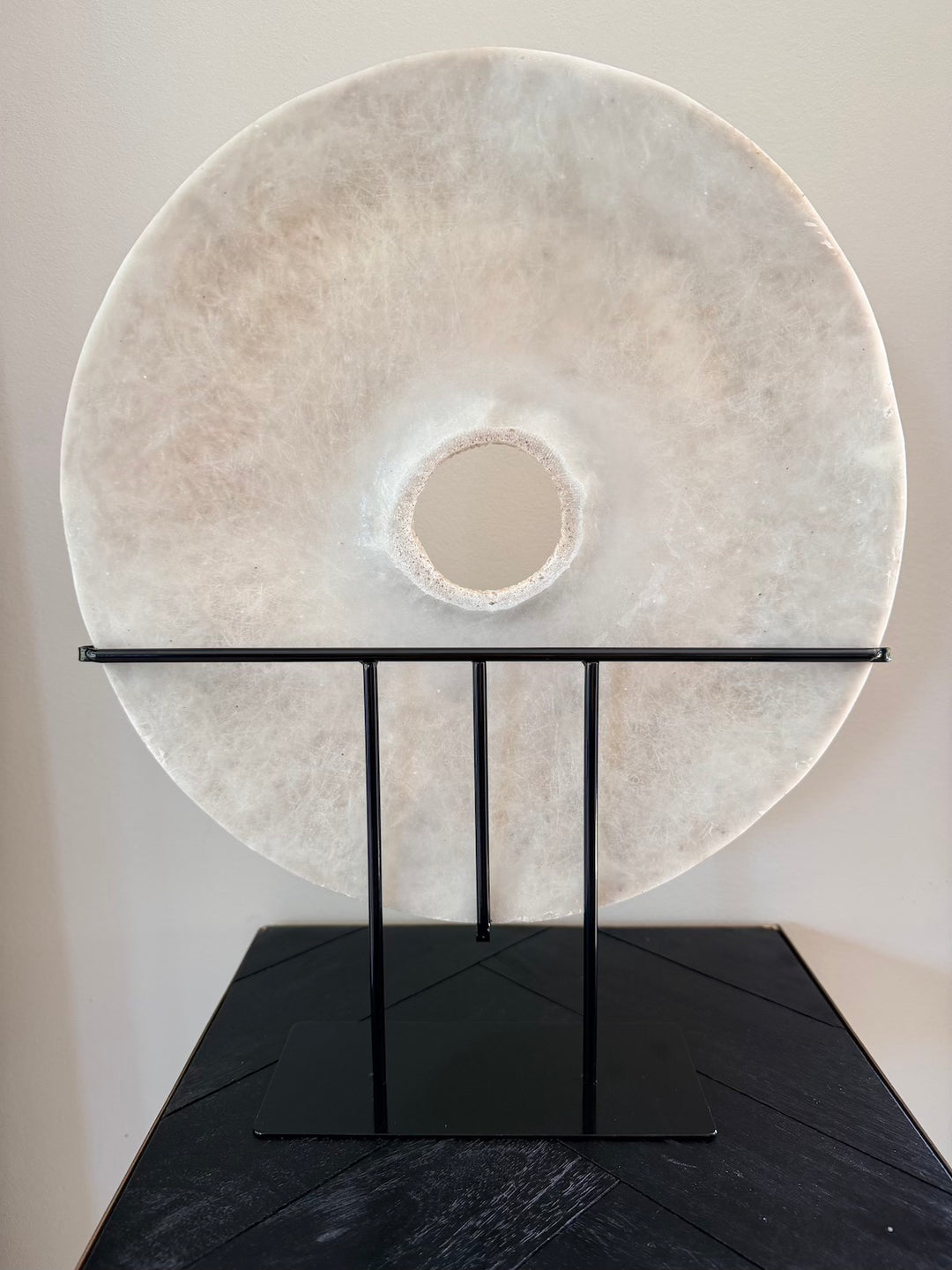 Achterzijde van ronde zandstenen decoratie op zwarte metalen standaard