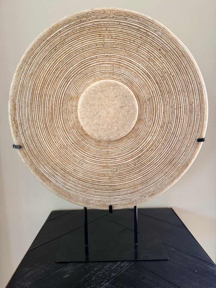 Bruine zandstenen decoratie op standaard met rond reliëf en zwarte voet