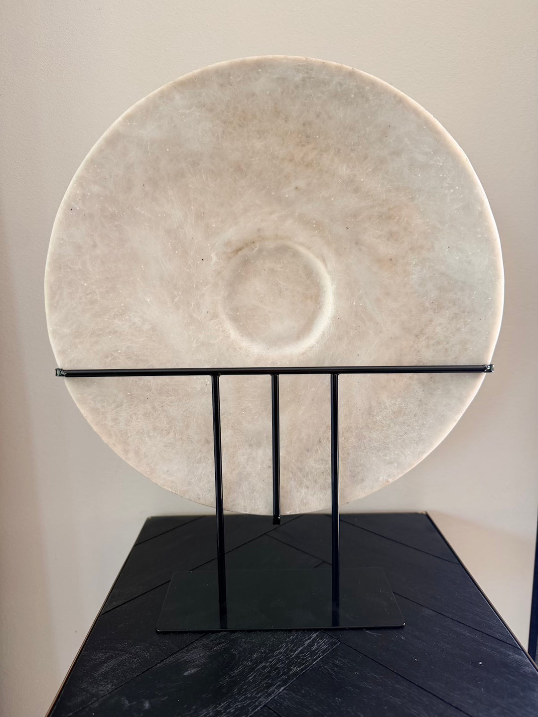 Achterzijde van ronde zandstenen decoratie op zwarte metalen standaard
