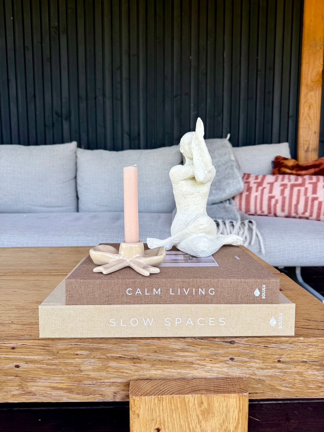 Decoratieset Calm Yoga Living met opbergboeken, yoga beeld en strik kandelaar op houten tuintafel