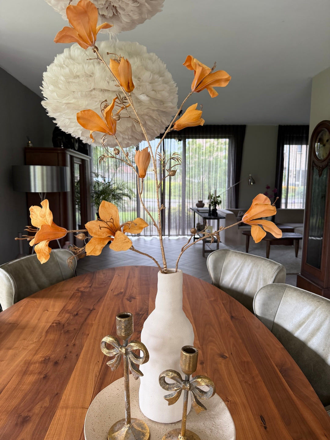 Beige woondecoratie set met amberkleurige takken en gouden accessoires op houten eettafel