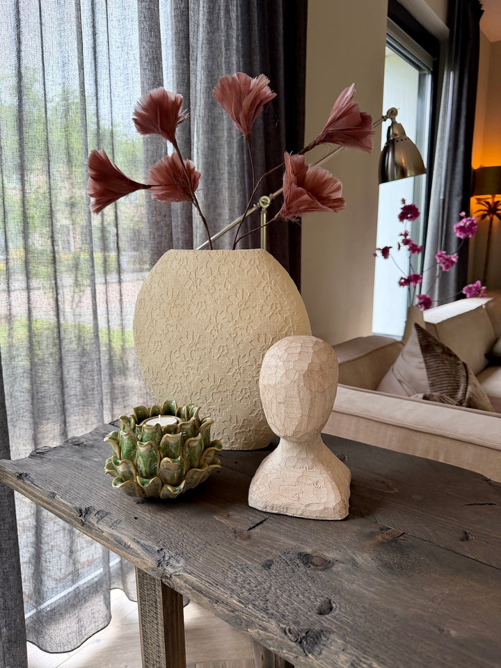 Sfeervolle interieurstyling met crème sculptuurvaas, kunsttakken en modern ornament hoofd