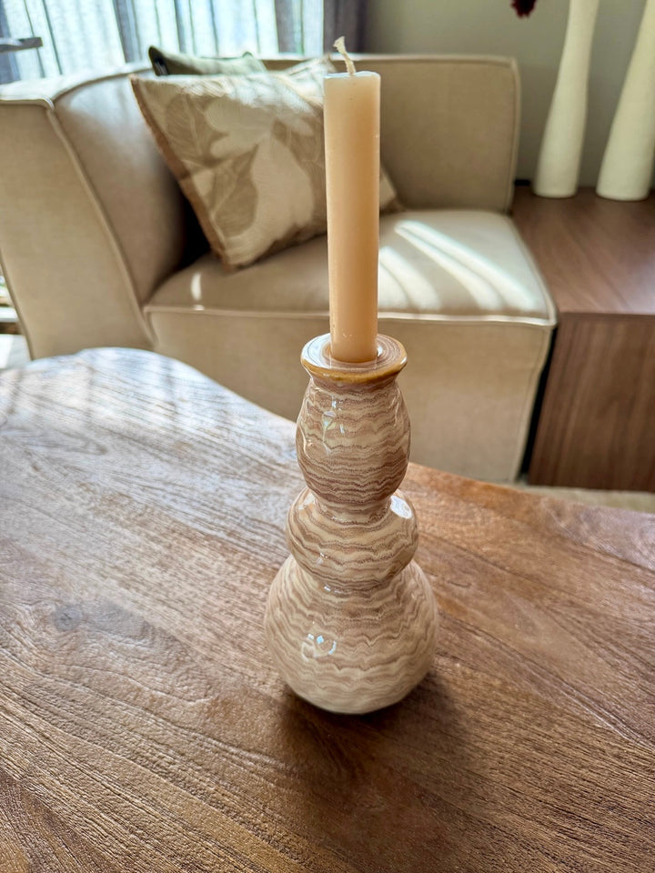 Zandkleurige kandelaar met dinerkaars op een houten tafel