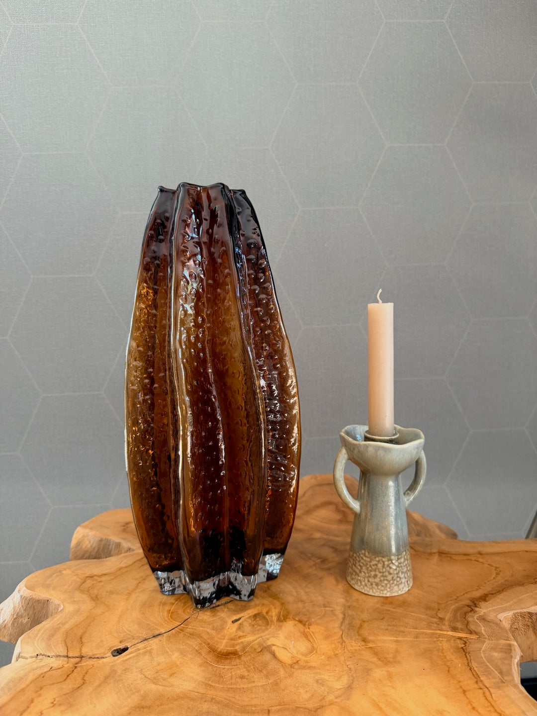 Amberkleurige glazen vaas van 35 cm hoog naast een keramieken kandelaar