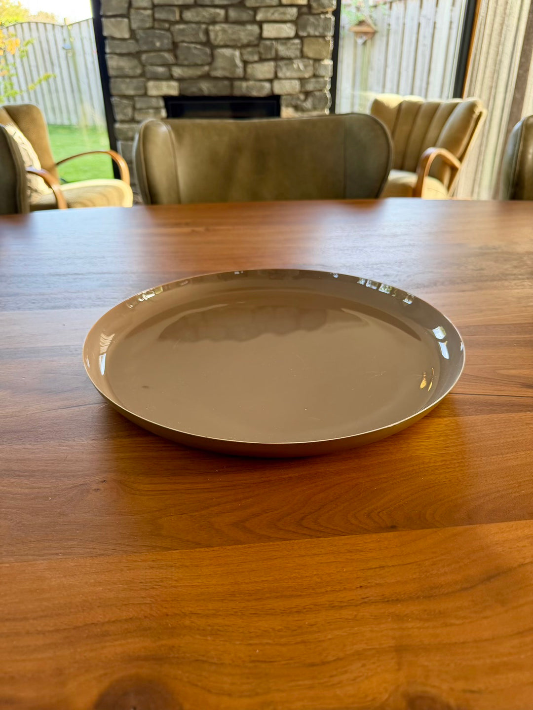 Rond taupe metalen plateau van 34 cm op een houten tafel