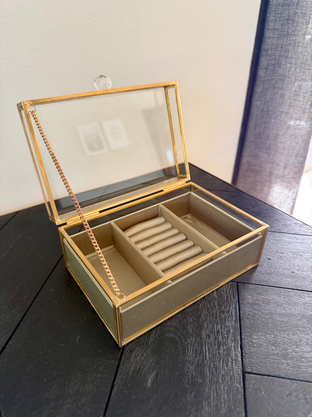 Geopend sieradendoosje met goudkleurig metalen frame, ringrollen en twee zijvakken